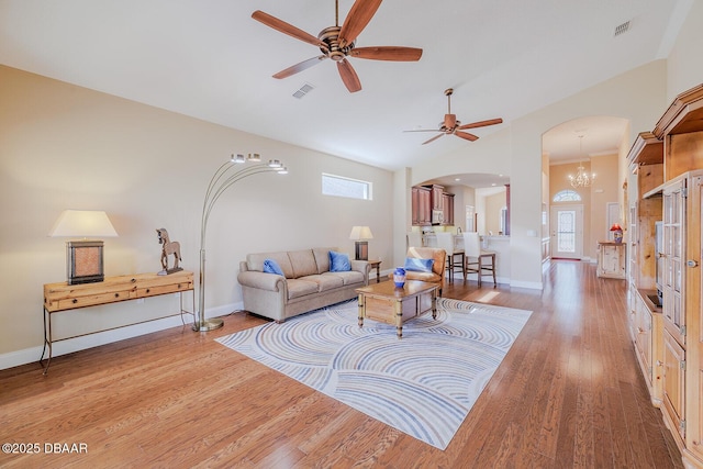 living room featuring ceiling fan with notable chandelier, vaulted ceiling, and light hardwood / wood-style floors