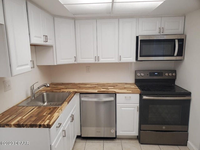 1504 Virginia Ave Unit 112, Daytona Beach, FL 32114 - kitchen featuring appliances with stainless steel finishes, wooden counters, white cabinetry, a sink, and light tile patterned flooring