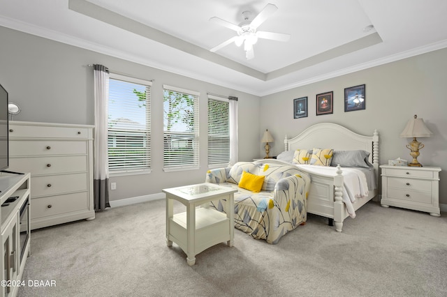 bedroom featuring a tray ceiling, light carpet, ceiling fan, and crown molding