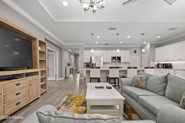 living room with light hardwood / wood-style floors, a notable chandelier, and ornamental molding