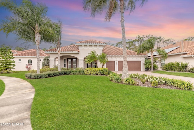 mediterranean / spanish-style home with a lawn and a garage