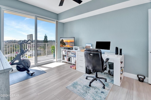 office with light wood-type flooring and ceiling fan