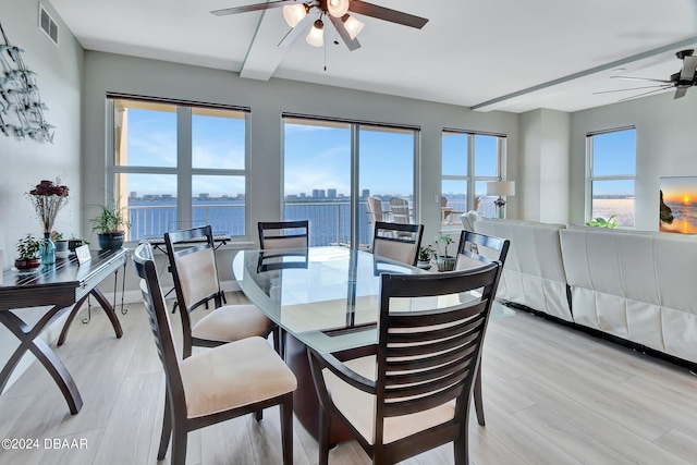 dining room featuring ceiling fan, a water view, and light hardwood / wood-style flooring