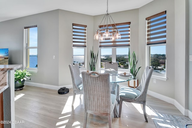 dining area with a wealth of natural light, a water view, and light hardwood / wood-style floors