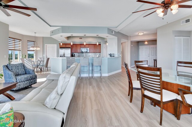 living room featuring light wood-type flooring and ceiling fan with notable chandelier