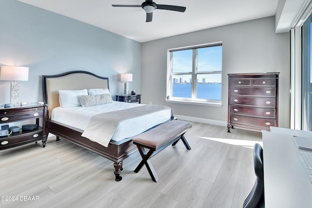 bedroom featuring a water view, ceiling fan, and light hardwood / wood-style flooring