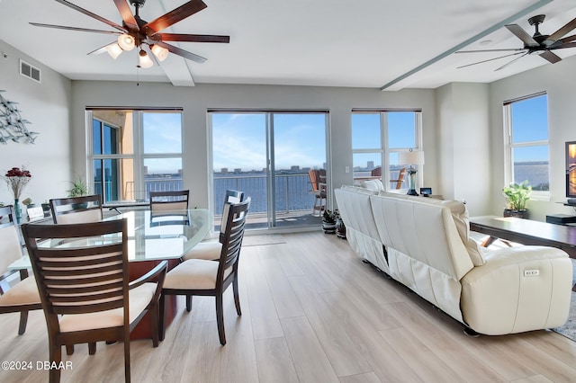 living room featuring ceiling fan, a water view, and light wood-type flooring