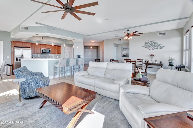 living room with sink, ceiling fan, and light hardwood / wood-style flooring