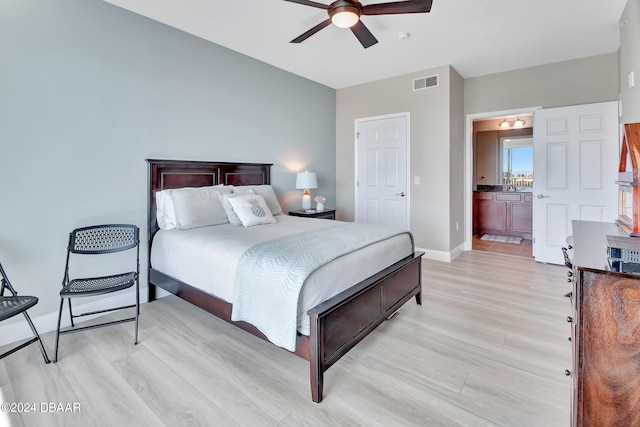 bedroom with ceiling fan, ensuite bath, and light wood-type flooring