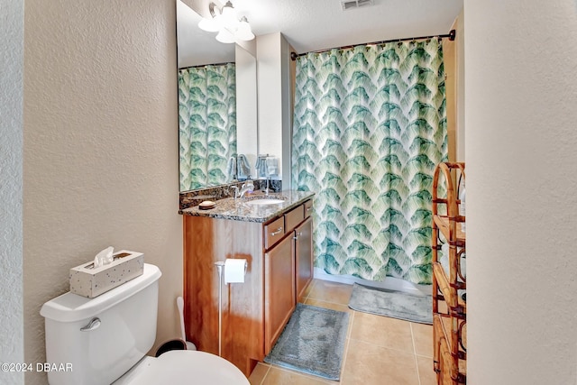 bathroom featuring vanity, tile patterned floors, toilet, and a textured ceiling