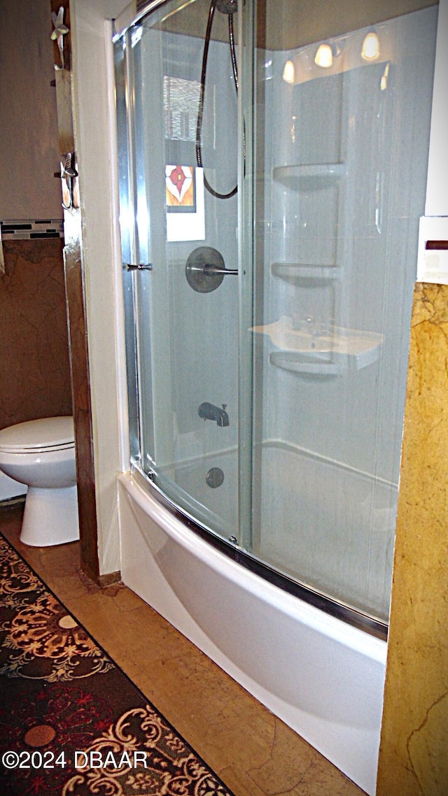 bathroom with bath / shower combo with glass door and toilet