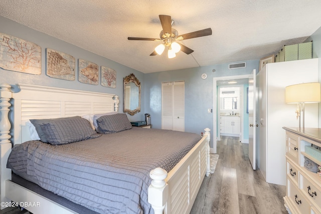 bedroom with a textured ceiling, light wood-type flooring, a closet, and ceiling fan