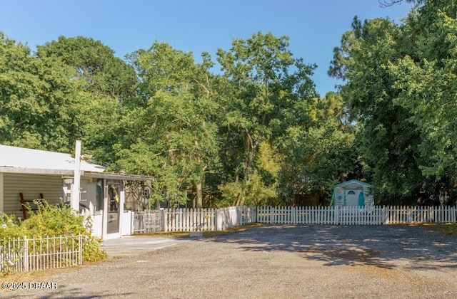 view of gate featuring a fenced front yard and a storage unit