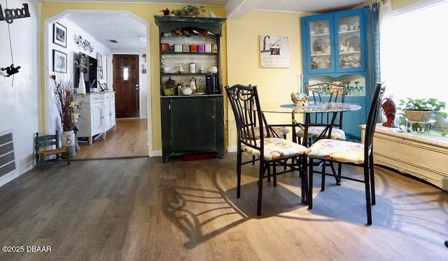 dining space featuring baseboards, arched walkways, and dark wood finished floors