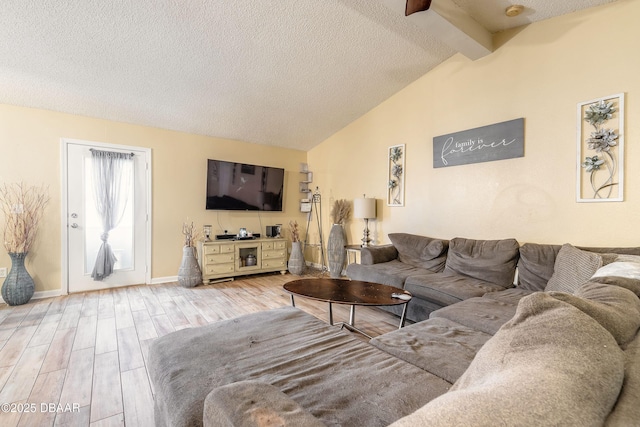 living room featuring light wood-type flooring, a textured ceiling, and lofted ceiling with beams