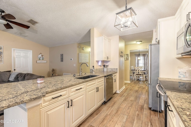 kitchen with ceiling fan with notable chandelier, decorative light fixtures, stainless steel appliances, sink, and light stone counters