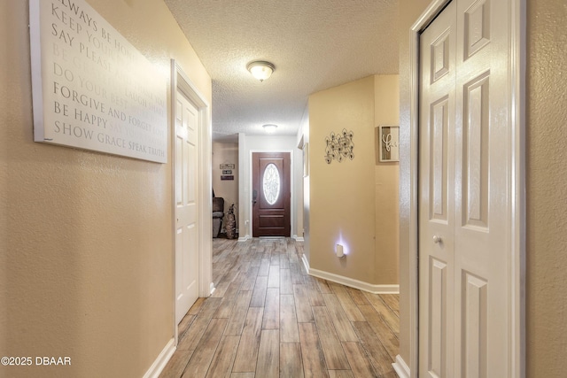 doorway with light wood-type flooring and a textured ceiling