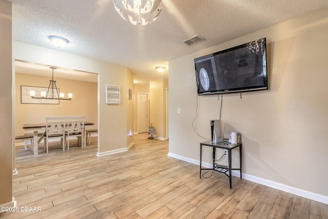 interior space with an inviting chandelier, light hardwood / wood-style floors, and a textured ceiling