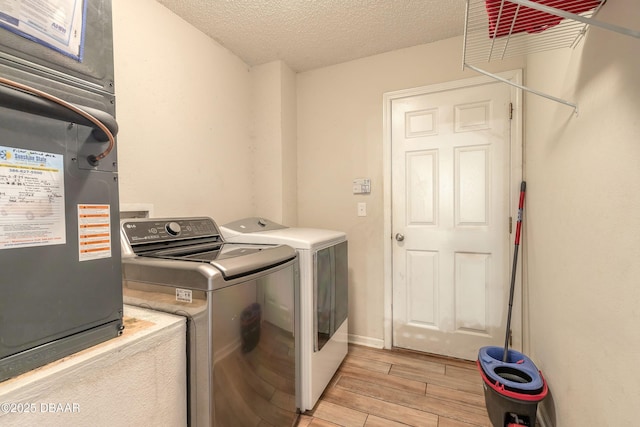 clothes washing area with a textured ceiling, heating unit, and washer and clothes dryer