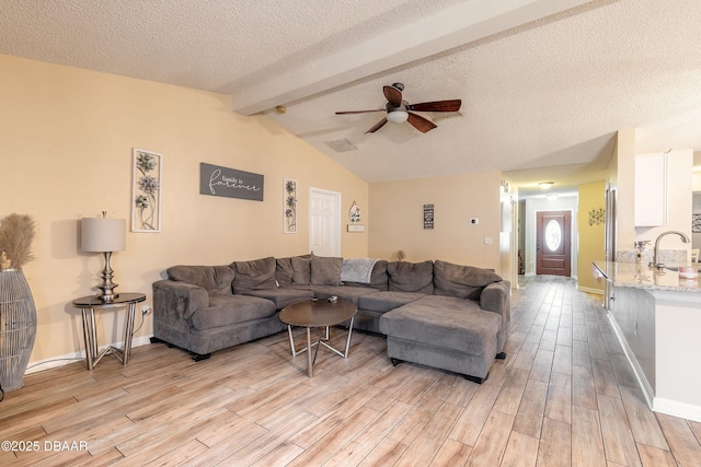 living room with sink, a textured ceiling, vaulted ceiling with beams, and ceiling fan