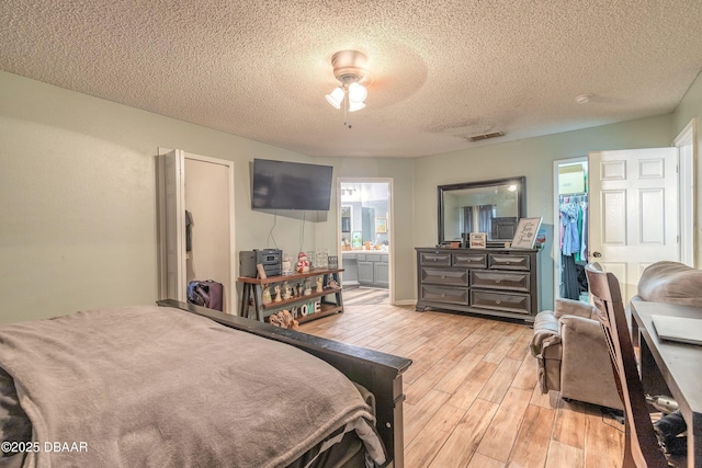 bedroom with a spacious closet, light hardwood / wood-style floors, a closet, ceiling fan, and connected bathroom