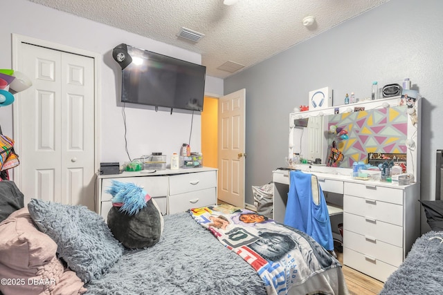 bedroom with a closet, light hardwood / wood-style flooring, and a textured ceiling