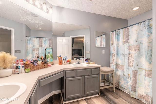 bathroom featuring wood-type flooring, curtained shower, a textured ceiling, and vanity