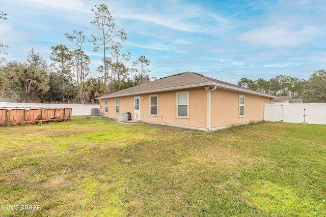 back of property with central air condition unit and a yard