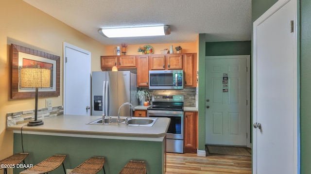 1401 S Palmetto Ave Unit 402, Daytona Beach, FL 32114 - kitchen with stainless steel appliances, light wood-style floors, a peninsula, backsplash, and a kitchen bar