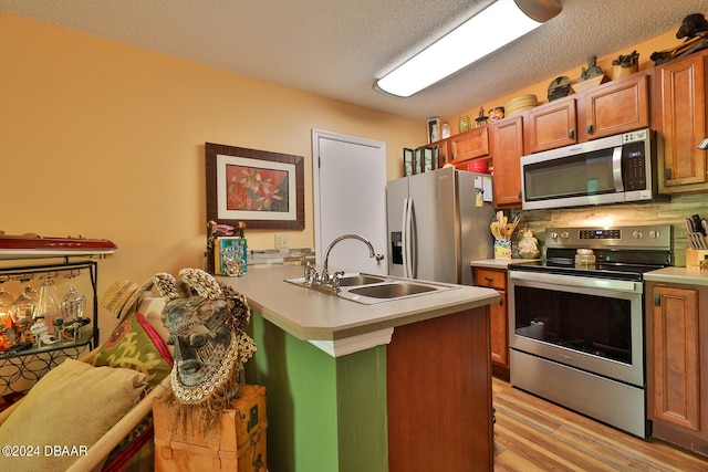 kitchen featuring light hardwood / wood-style floors, sink, appliances with stainless steel finishes, a textured ceiling, and backsplash