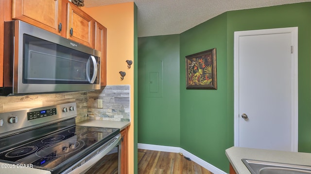 1401 S Palmetto Ave Unit 402, Daytona Beach, FL 32114 - kitchen with stainless steel appliances, wood finished floors, brown cabinets, electric panel, and light countertops