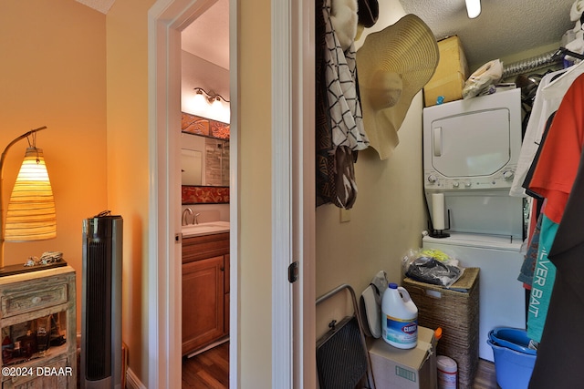 bathroom with stacked washer / dryer, vanity, a textured ceiling, and wood-type flooring