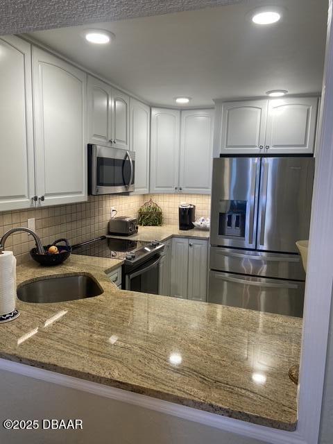 kitchen featuring stainless steel appliances, sink, dark stone counters, and white cabinets