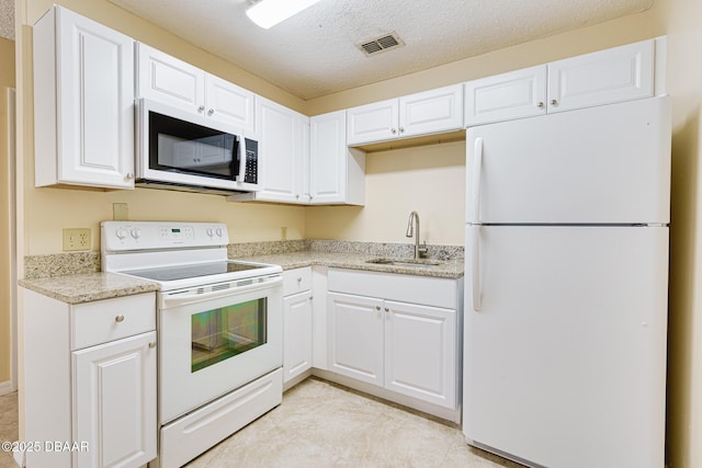 kitchen with a sink, visible vents, white cabinetry, white appliances, and light stone counters