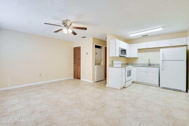 kitchen featuring a sink, stacked washing maching and dryer, white appliances, ceiling fan, and light countertops
