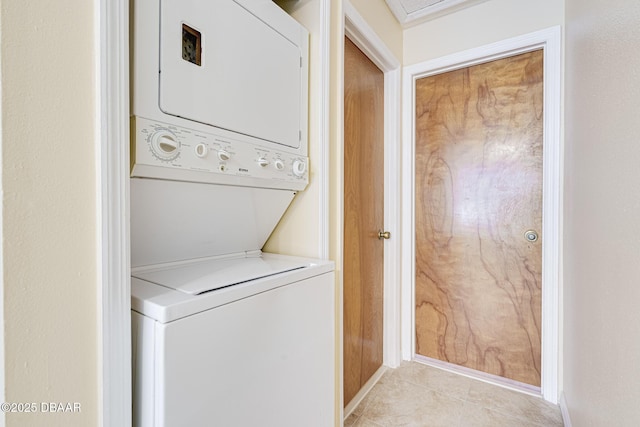 clothes washing area featuring stacked washer / drying machine, light tile patterned flooring, and laundry area