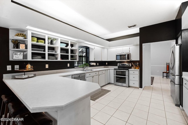 kitchen with white cabinetry, sink, stainless steel appliances, kitchen peninsula, and light tile patterned floors