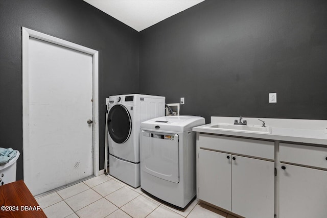 washroom with cabinets, light tile patterned floors, washer and clothes dryer, and sink