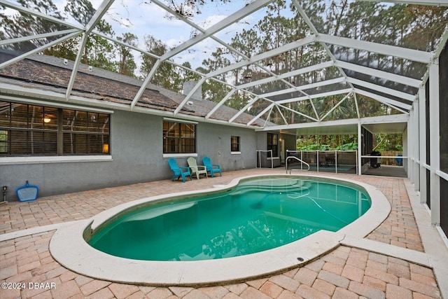 view of swimming pool with glass enclosure and a patio