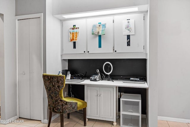 bar featuring white cabinets, light tile patterned floors, and built in desk