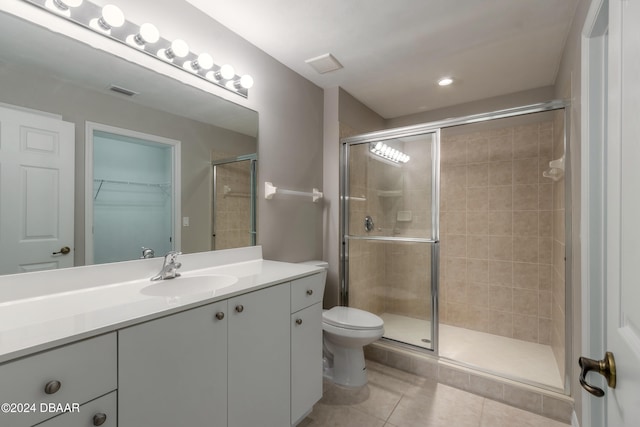 bathroom with toilet, vanity, tile patterned floors, and a shower with shower door