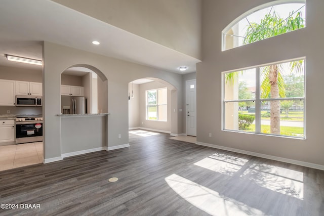 unfurnished living room with light hardwood / wood-style floors and a high ceiling