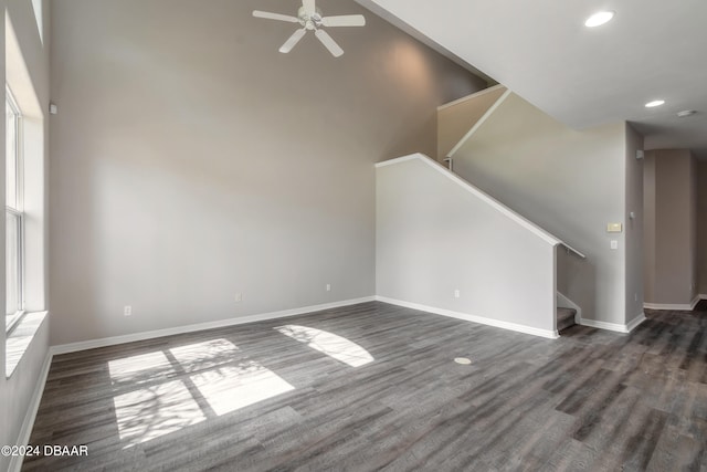 unfurnished living room featuring ceiling fan, a high ceiling, and dark hardwood / wood-style floors