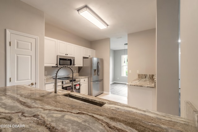 kitchen featuring light hardwood / wood-style floors, radiator, white cabinetry, appliances with stainless steel finishes, and decorative light fixtures