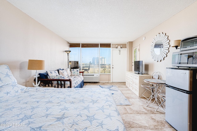 bedroom with stainless steel fridge, a textured ceiling, and floor to ceiling windows