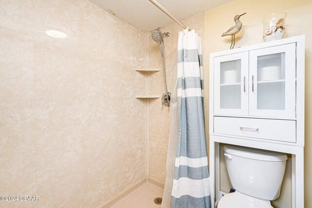 bathroom with a shower with shower curtain and toilet