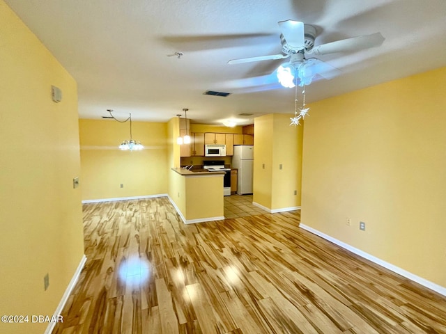 unfurnished living room with ceiling fan with notable chandelier and light hardwood / wood-style flooring