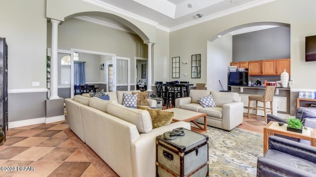 tiled living room featuring crown molding, a high ceiling, and ornate columns