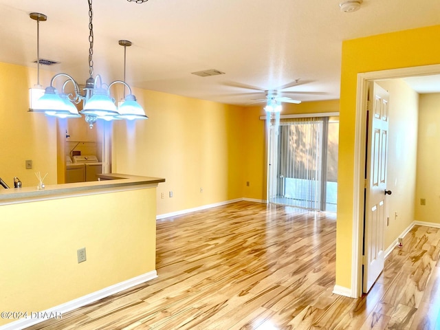 interior space with washer and dryer, light hardwood / wood-style flooring, and ceiling fan with notable chandelier