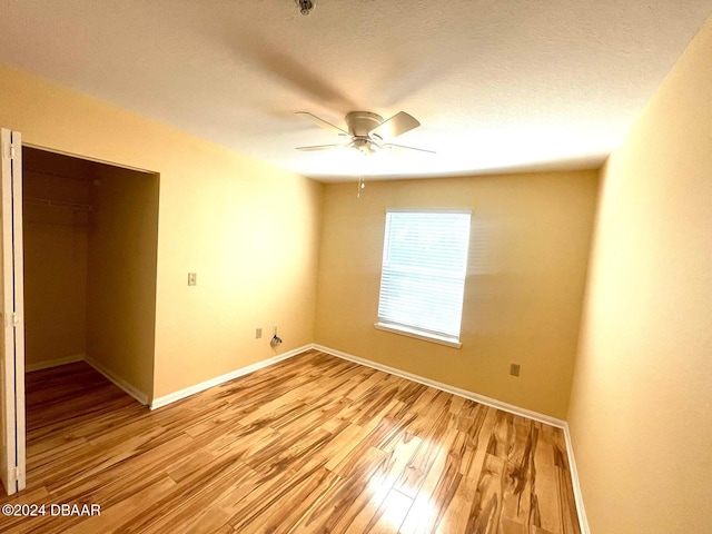 unfurnished bedroom with a closet, light wood-type flooring, a textured ceiling, and ceiling fan